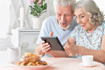 Canvas Print - portrait of happy beautiful senior couple holding tablet