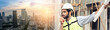 Banner size. Young attractive construction man in vest with white helmet use radio and holds blueprint while standing on building construction site. Home building project.