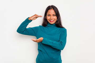 Wall Mural - Young Indian woman isolated on white background holding something little with forefingers, smiling and confident.