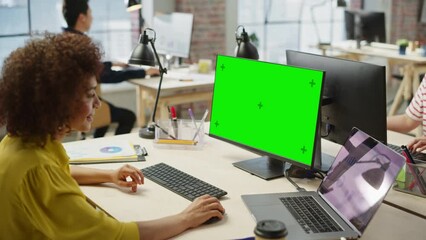Wall Mural - portrait of biracial creative young woman working on a green screen in bright busy office during day