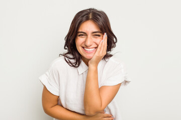 Wall Mural - Young Indian woman isolated on white background laughs happily and has fun keeping hands on stomach.