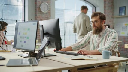 Poster - Portrait of Creative Bearded White Man with Glasses Focused While Using Computer in Bright Spacious Office. Marketing Manager Building a New Strategy. Dolly Shot.