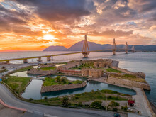 Aerial View Of Rio (Rion) Fortress Near Patras And The Rion-Antirion Bridge Greece Protecting And Crossing The Entrance To The Gulf Of Corinth With Magical Colorful Sunset
