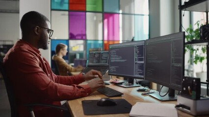Fototapete - Black Man Writing Lines of Code On Desktop PC With Two Monitors and a Laptop Aside in Stylish Office. Professional Male Developer Programming Artificial Inteligence Software for Start-Up Company.