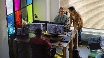 Wall Mural - Stylish Office Space: Diverse Team Of Developers Writing Code On Desktop Computers With Multiple Monitors. Female Start-up Founder Talks to Senior Data Scientist While Junior Colleagues Coding.