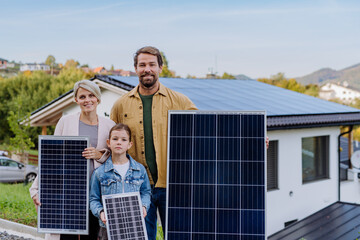 Wall Mural - Happy family near their house with solar panel. Alternative energy, saving resources and sustainable lifestyle concept.