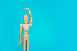 yellow wooden mannequin shows hand gestures on a blue background