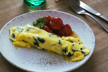 Wall Mural - Omelet with spinach and roasted cherry tomatoes on wooden table, healthy breakfast