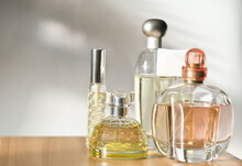 Various Woman Perfumes Set On Light Background With Shadows. Selective Focus On Front Bottle