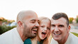 © Vane Nunes - Happy gay fathers having fun with their kid outdoor - Lgbtq family and love concept - Focus on right dad face