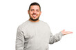 © Asier - Young caucasian man isolated showing a copy space on a palm and holding another hand on waist.
