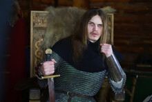 A Mighty Hero With Long Hair In Chain Mail Armor In An Ancient Hall. Medieval Warrior In The Knight's Chambers.
