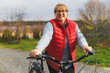 © SOLOTU - Middle aged smiling mature woman holdingt a bike with her hands on the grass on a green field. Summer or Autumn Country Vacation and Adventure Concept