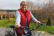 © SOLOTU - Middle aged smiling mature woman holdingt a bike with her hands on the grass on a green field. Summer or Autumn Country Vacation and Adventure Concept