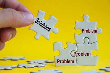 problem and solutions text on jigsaw with one hand holding a missing jigsaw pieces.