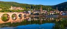 Heidelberg Wide Angle Old Town Panorama With Castle, “Karl Theodor Bridge“ And Its Twin Tower Gate, Church Of The Holy Spirit. Reflection In The Water Of River Neckar On A Sunny Summer Day In Germany.