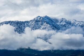 Sticker - Beautiful scene of fog over a snowy mountain under cloudy sky