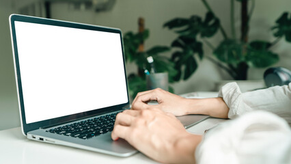 Asian man working on a laptop computer with white mock-up screen. Work at home office