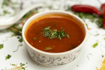 Poster - Closeup of a small plate of delicious red soup surrounded by groceries and ingredients