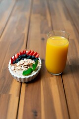 Wall Mural - Closeup of a bowl of cereal with fresh fruits, nuts and meant leaves with a glass of orange juice