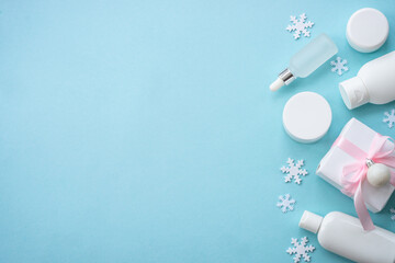 Poster - Natural winter cosmetic with holiday decorations and present box on blue background. Winter scincare concept. Flat lay image.
