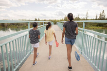 Sisters With Fishing Nets Walking On Footbridge Over River