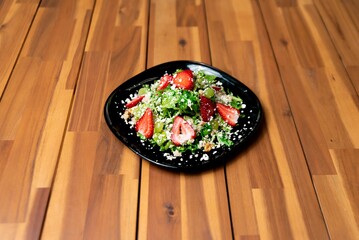 Canvas Print - Closeup of salad with greens and strawberries and cottage cheese on a wooden table