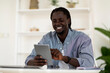 © Prostock-studio - Modern Technologies. Cheerful Young Black Man Using Digital Tablet At Home