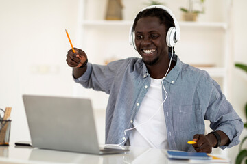 Cheerful Black Guy Having Fun While Listening Music On Laptop At Home