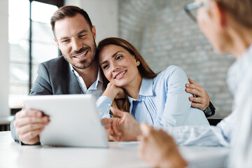 Wall Mural - Happy couple using digital tablet while having a meeting with their insurance agent in the office