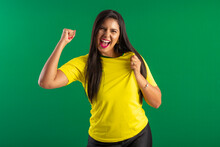 Woman Brazilian Fan. Wearing Brazilian Shirt In A Portrait, Brazilian Fan Celebrating Football Or Soccer Game On Green Background. Colors Of Brazil.World Cup