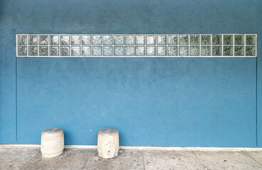 Blue Gray Wall with Glass Cube Sunlight and Two White Cement Stools.