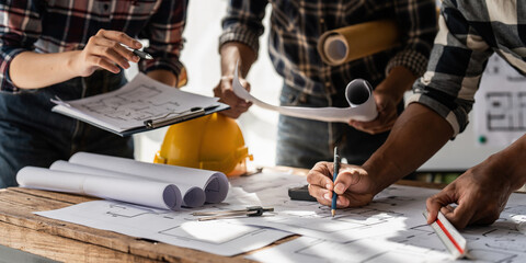 Architect team working with blueprints for architectural plan, engineer sketching a construction project, green energy concept