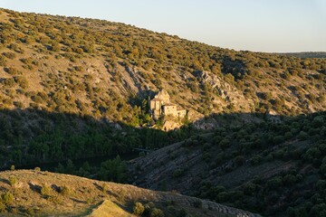 Hermitage of San Saturio hillside chapel in sunlight with a blue sky in the background, Soria, Spain