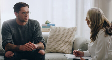 Wall Mural - Therapy, man and therapist talking about mental health during a consultation in an office. Depression, communication and psychologist consulting with sad patient about anxiety or problem of the mind