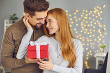 Thank You, Sweetheart. Happy Couple In Love Hugging While Celebrating Saint Valentine Day Or Relationship Anniversary At Home. Young Woman Holding Gift Box And Thanking Her Boyfriend For The Gift