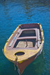 Wooden Dinghy. Copy Space. Weathered empty fishing boat in calm blue waters. Stock Image.