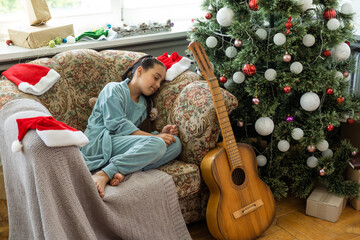 Wall Mural - Merry Christmas and Happy Holidays. Cute little child girl is decorating the Christmas tree indoors.