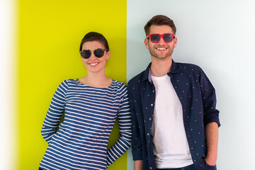 Wall Mural - Modern man and girl wearing sunglasses posing isolated in front of colorful background