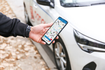 Warszaw, Poland - August, 2022: young person on a smartphone books a car in the Panek carsharing app to get around the city. New generation chooses not to own a car but to rent a vehicle