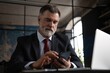 © opolja - Mature business man in formal clothing using mobile phone. Serious businessman using smartphone and laptop at work