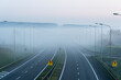 pusta niebieska mglista deszczowa autostrada z niską słabą widocznością w zimny wiosenny jesienny poranek. Sezonowa zła pogoda deszczowa ostrzeżenie o niebezpieczeństwie wypadku