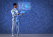 © IndiaPix - A man wearing silver, futuristic  clothes holding digital tablet, and looking at a virtual screen. A future technology concept
