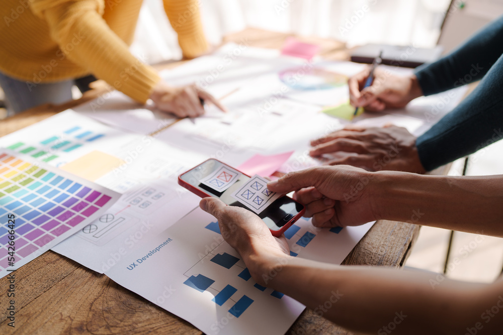 A UX design team is a confluence of user research, UX, UI design with layout paper on desk.