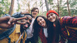 © silverkblack - Multiracial group of friends travelers is taking selfie in wood looking at camera, posing with funny faces and trendy gestures. Millennials are wearing modern tourist outfit.