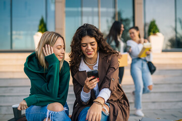 Wall Mural - caucasian female students at university campus using mobile phone