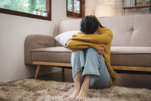 Young Asian Woman Suffering From Work Stress Sits Alone On The Sofa At Home Discouraged. Desperate Asian Woman Feeling Lonely