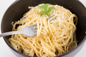 Sticker - Yellow pepper pesto spaghetti covered with grated mozzarella cheese decorated with coriander being rolled around a fork