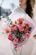 Very nice young woman holding beautiful bouquet of fresh eucalypts, roses, baby breath, eustoma, Protea, tender flowers in pink colors, cropped photo, bouquet close up