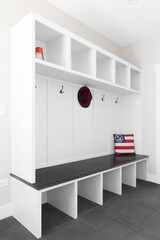 Wall Mural - A white mud room foyer with a dark grey tile floor, white shelving, coat hooks, and wood bench seat.